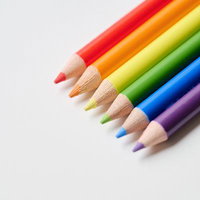 虹色に並んだ色鉛筆と白い背景に落ちた影の写真