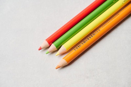 赤・緑・黄・橙の4色の色鉛筆が斜めに並べられた