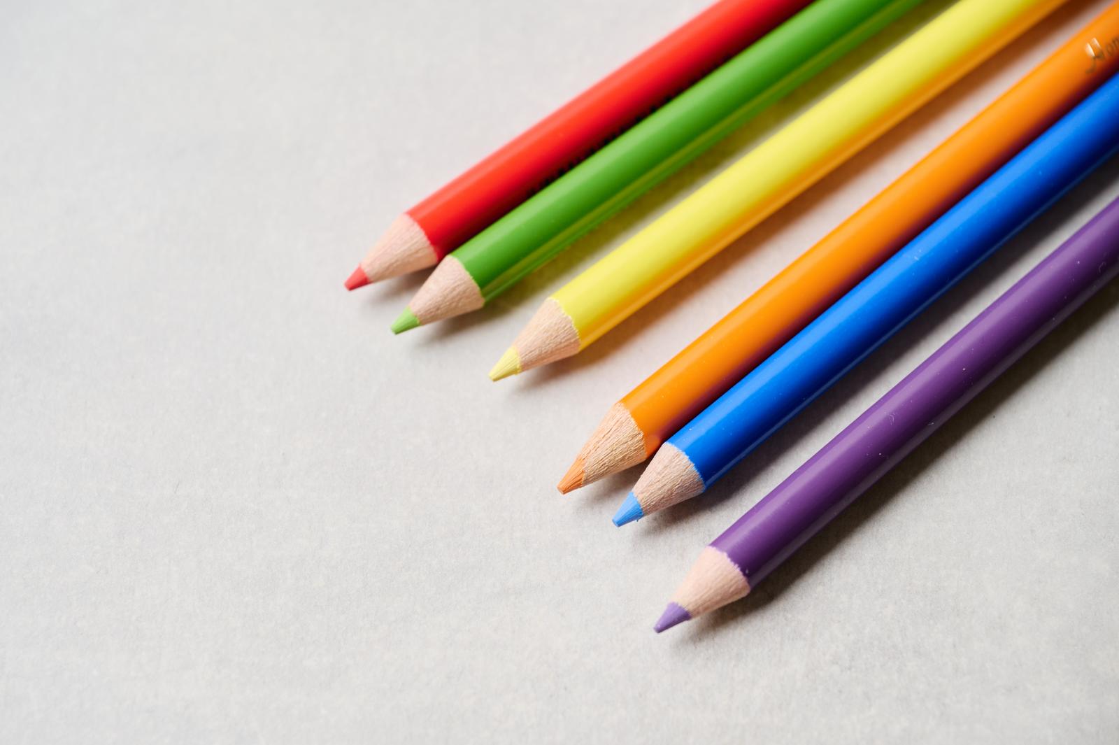虹色に揃ったカラフルな色鉛筆が白い背景に対角線上に並んでいる