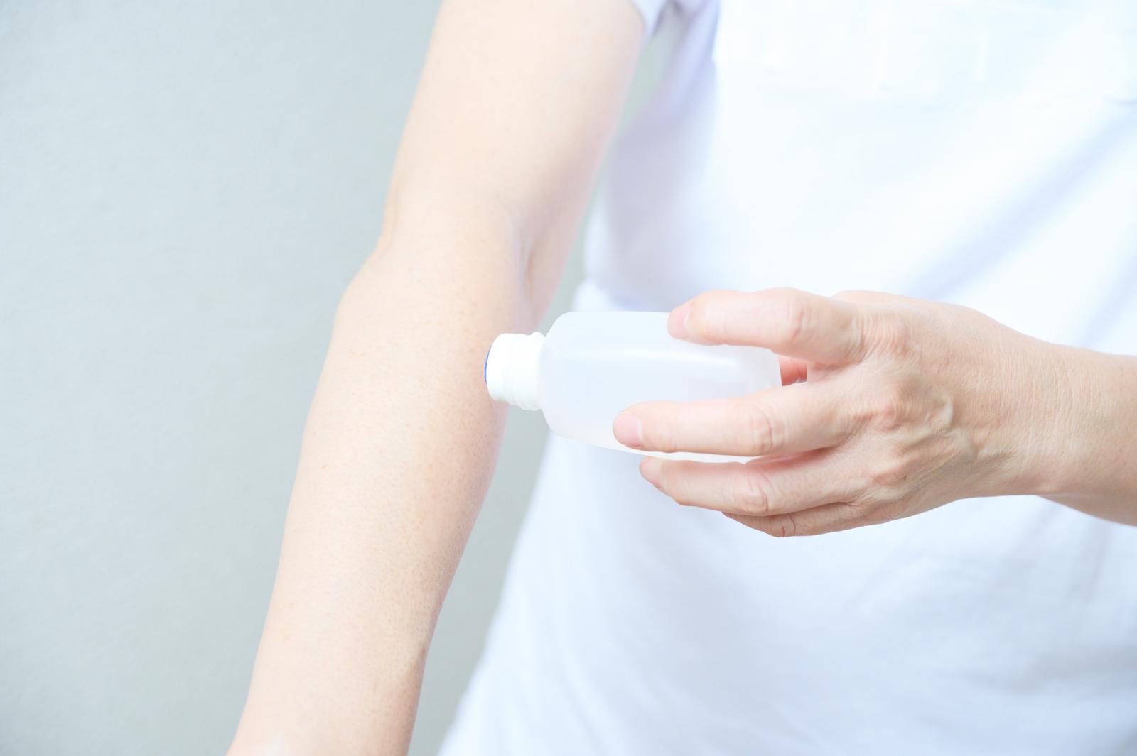 虫刺されの薬を腕に塗る女性の手元のアップ