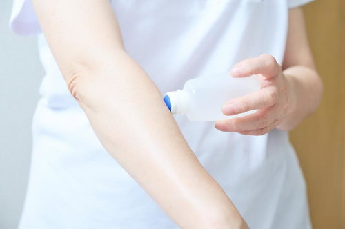 かゆみ止めローションを腕に塗る様子