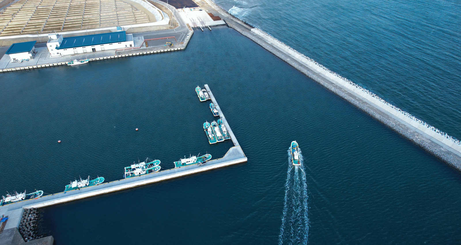 福島県請戸漁港に停泊する複数の白と青の漁船を上空から撮影した画像