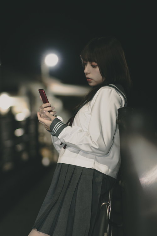 待ち合わせ場所でスマートフォンを確認する女子高生