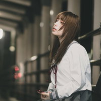 駅のホームで憂鬱な表情の女子高生、終電待ちの写真