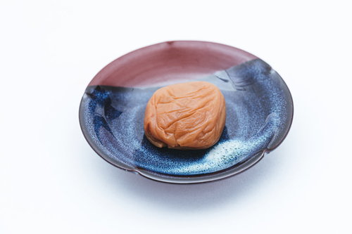 青い陶器の皿に盛られた梅干しの一粒、南高梅使用