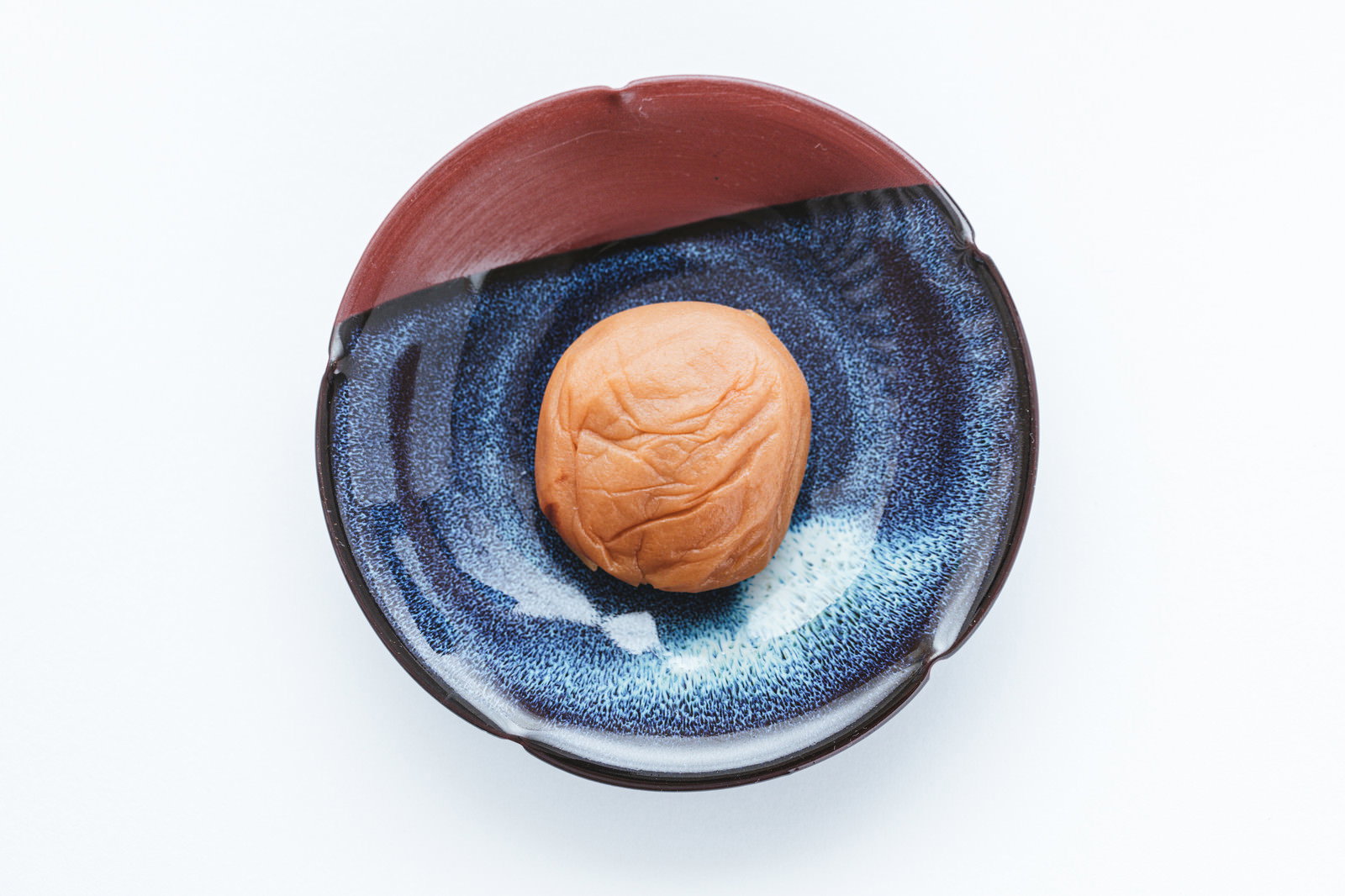 A single pickled plum placed on a blue plate