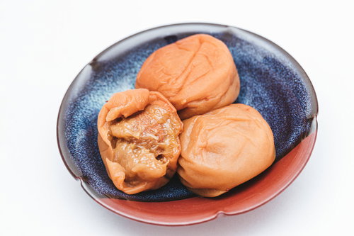青い縁取りの白いお皿に盛られた梅肉がのぞく南高梅の梅干し