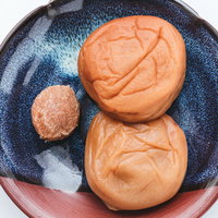 青い皿に盛られた梅干しと種、南高梅の和食食材の写真