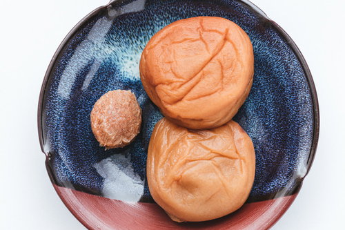 青い皿に盛られた梅干しと種、南高梅の和食食材