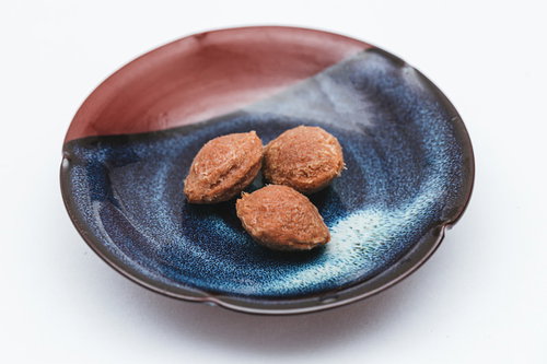 陶器の皿に盛られた梅干しの種3つと実、和食の定番食材
