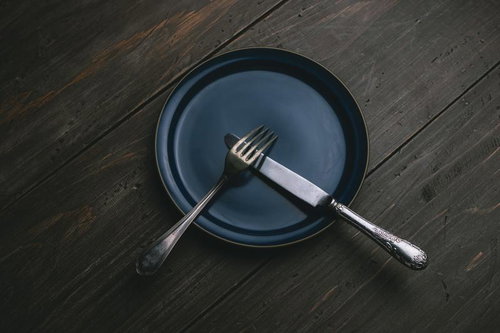 紺色の皿の上に置かれたナイフとフォークでテーブルマナーを表現