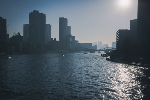霞みゆくビル群へと続く海と船舶が浮かぶ都市景観