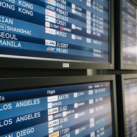 空港の電光掲示板に表示される海外行きフライト情報の写真