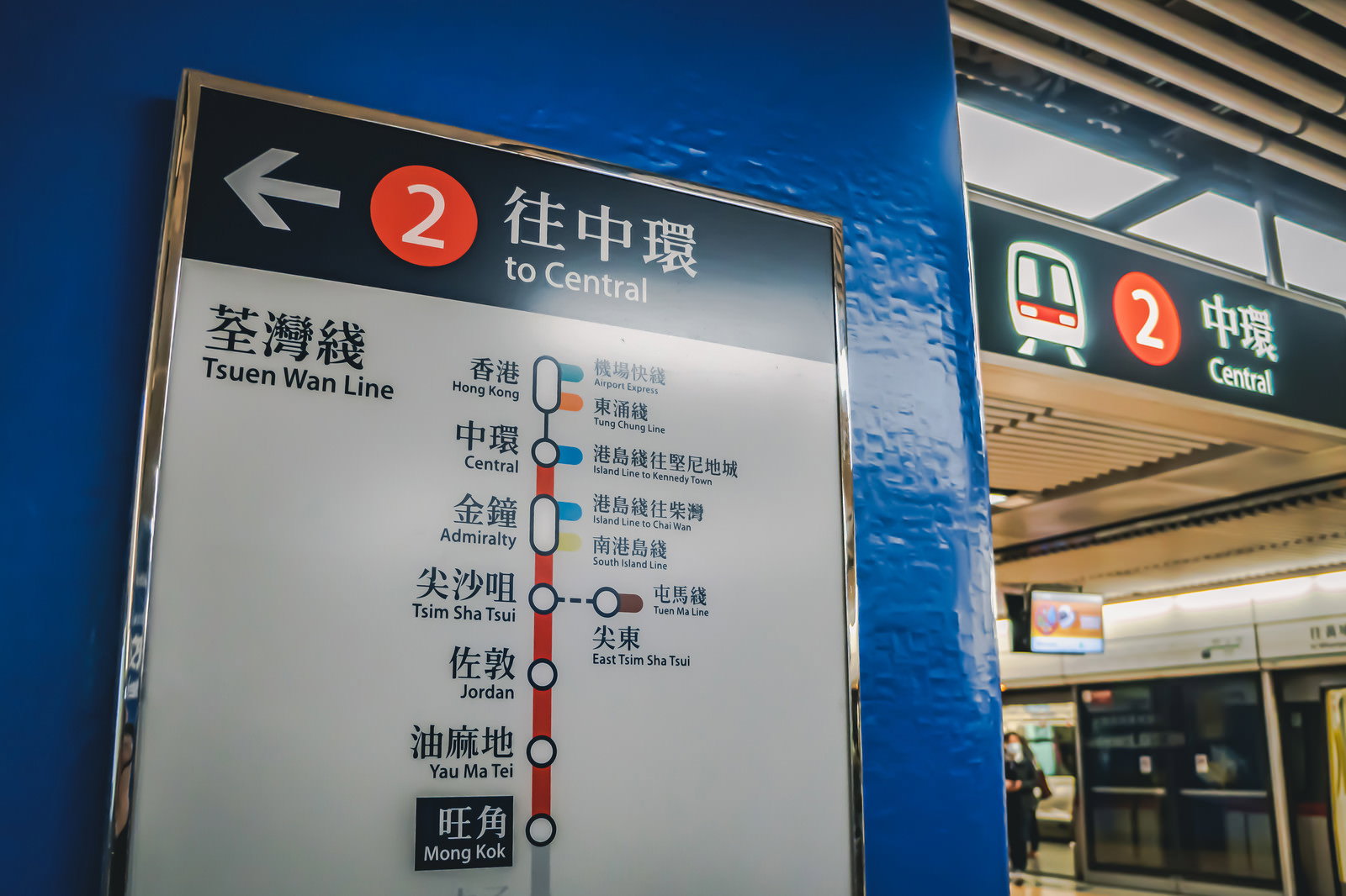香港の駅構内に設置された青い案内板と電車のホーム