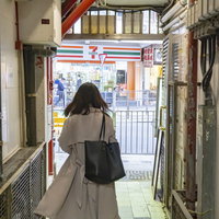 香港の雑居ビルから出てくる後ろ姿の女性の日常の写真