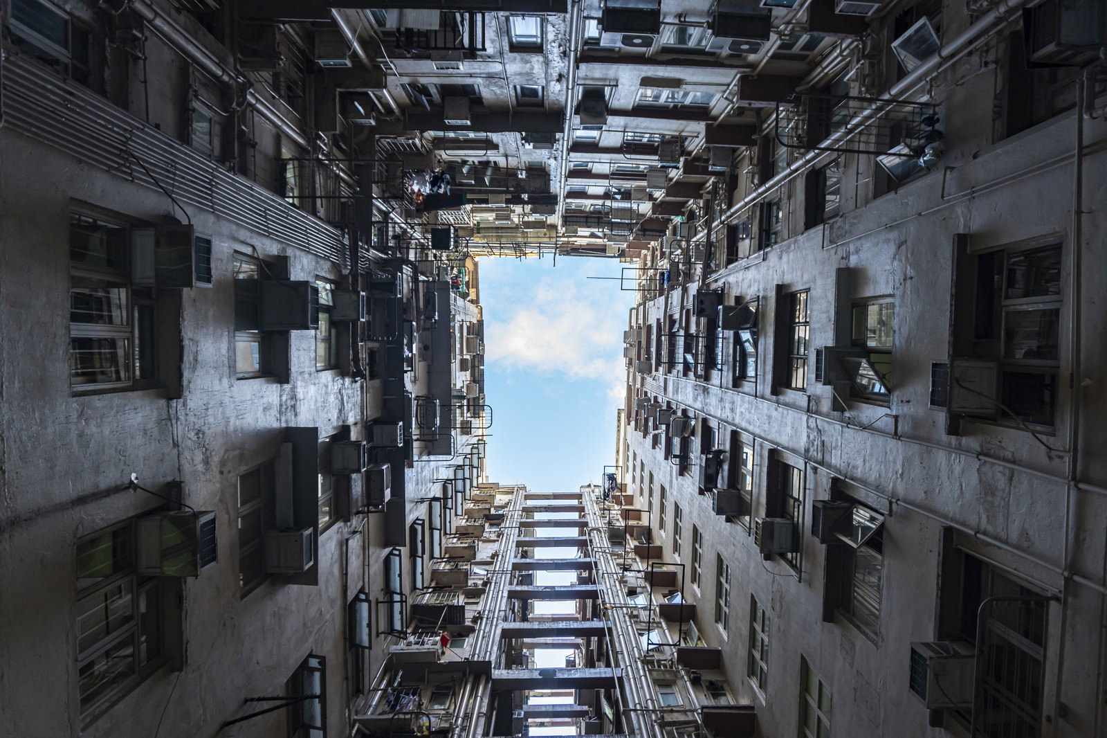 香港の雑居ビルを下から見上げた構図で密集した建物の間から空が見える