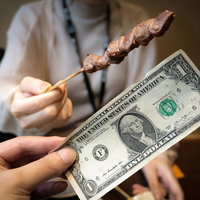 焼き鳥1本を1ドル紙幣で購入するシーンの経済比較の写真