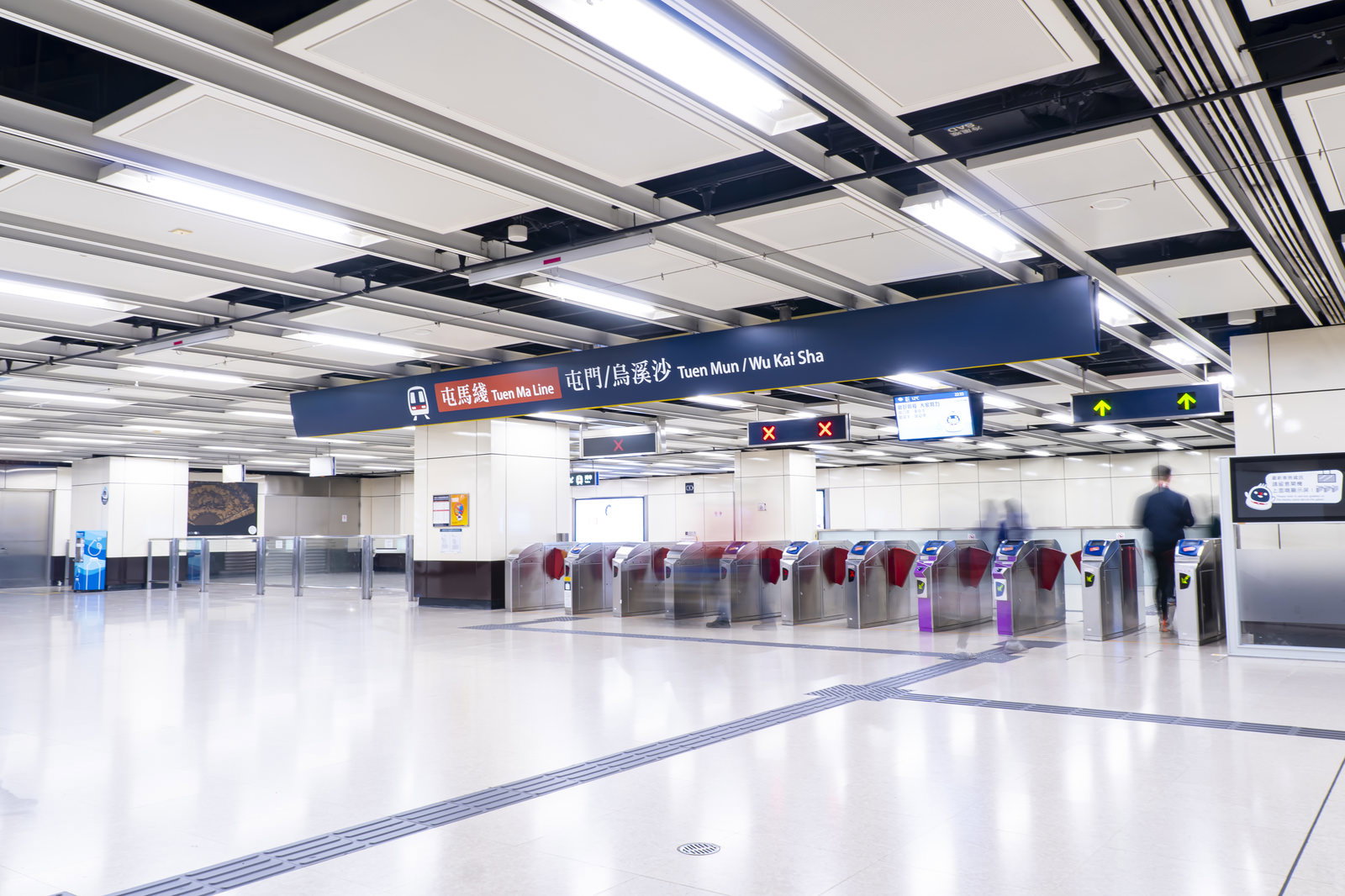 白い天井の駅構内に青い案内表示と改札機が並ぶ香港の尖東駅