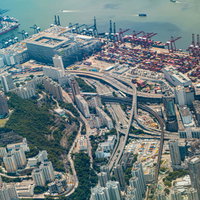 高層ビル群に囲まれた香港の港湾コンテナ埠頭の写真