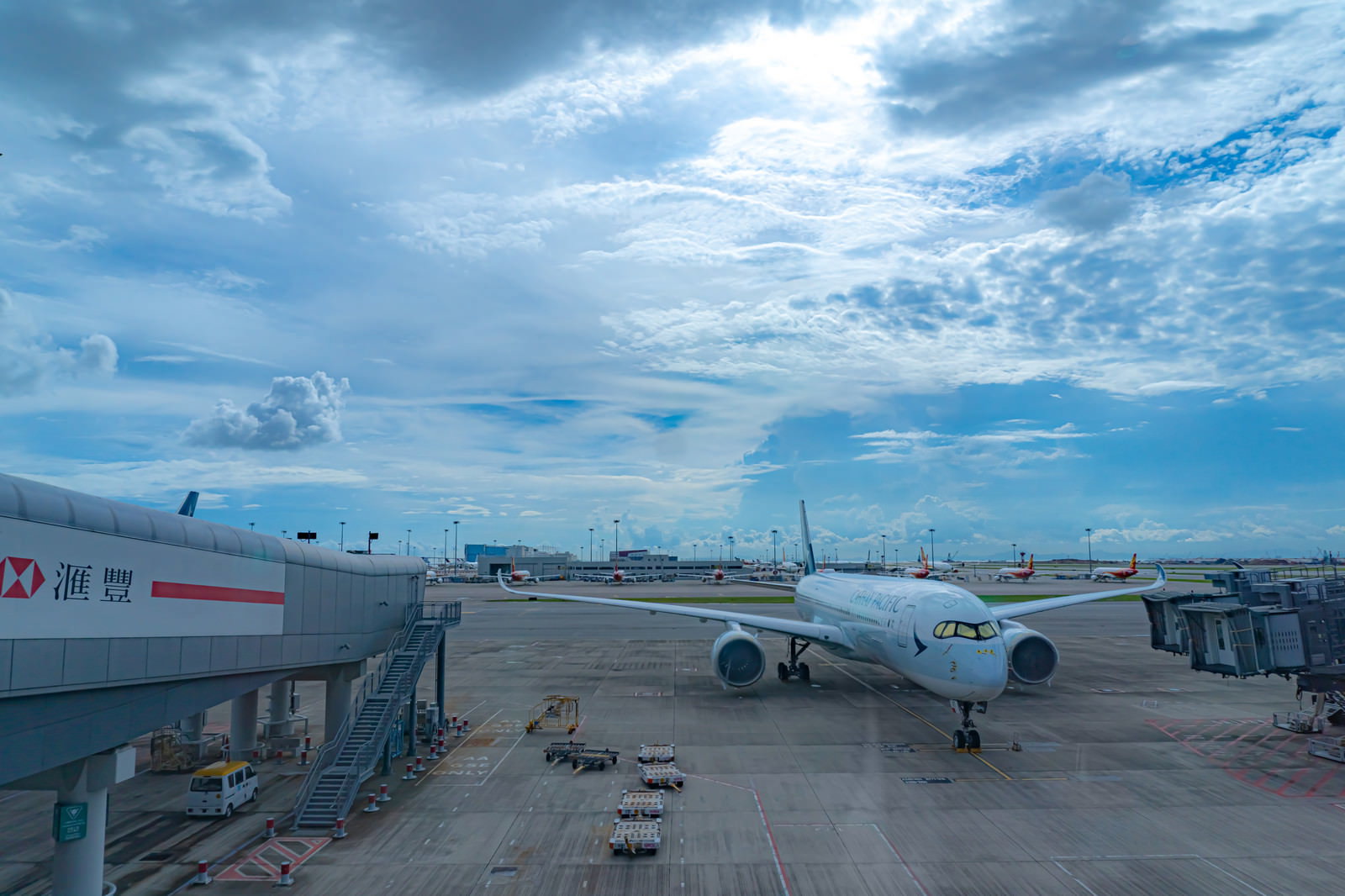 香港国際空港のターミナルから見た駐機場に停まる白い航空機と青空