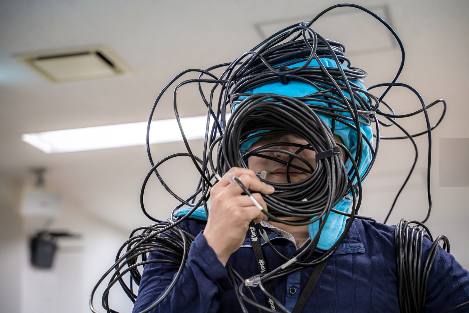 多数のLANケーブルが絡まった状態で頭を抱えるエンジニア