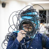 LANケーブルが頭に絡まった男性エンジニアの配線トラブルの写真