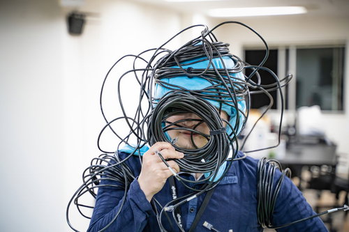 LANケーブルが頭に絡まった男性エンジニアの配線トラブル