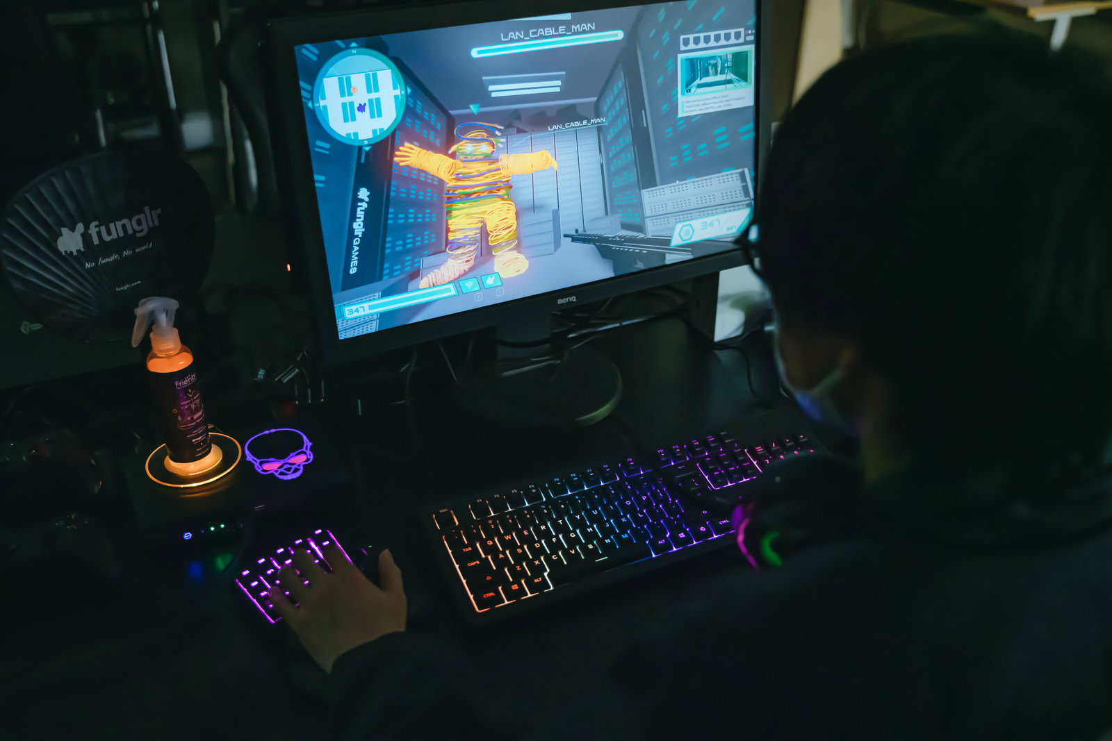 暗い部屋でPCゲームをプレイするゲーマーのデスク環境