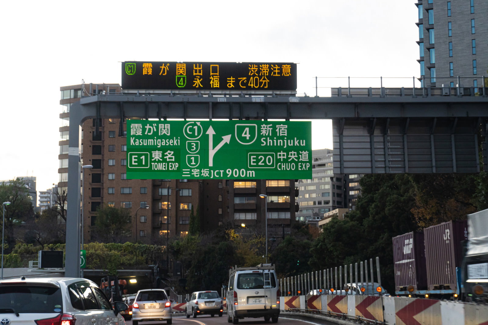 首都高速道路で緑色の案内標識の下を走行する複数の車両