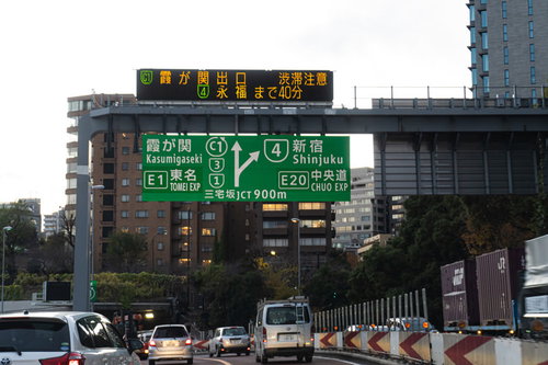 首都高速道路を走行しながら案内板を見る運転風景