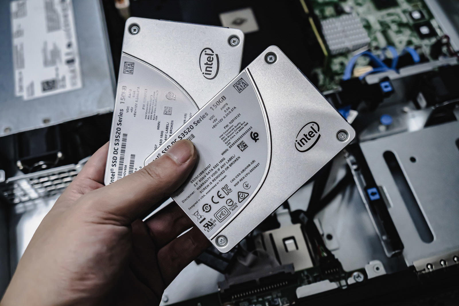 手にSSDを持ってサーバー機器の前で作業するデザイナー