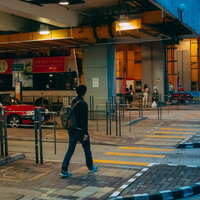 バス乗り場へ向かうリュックサック姿の香港男子の写真