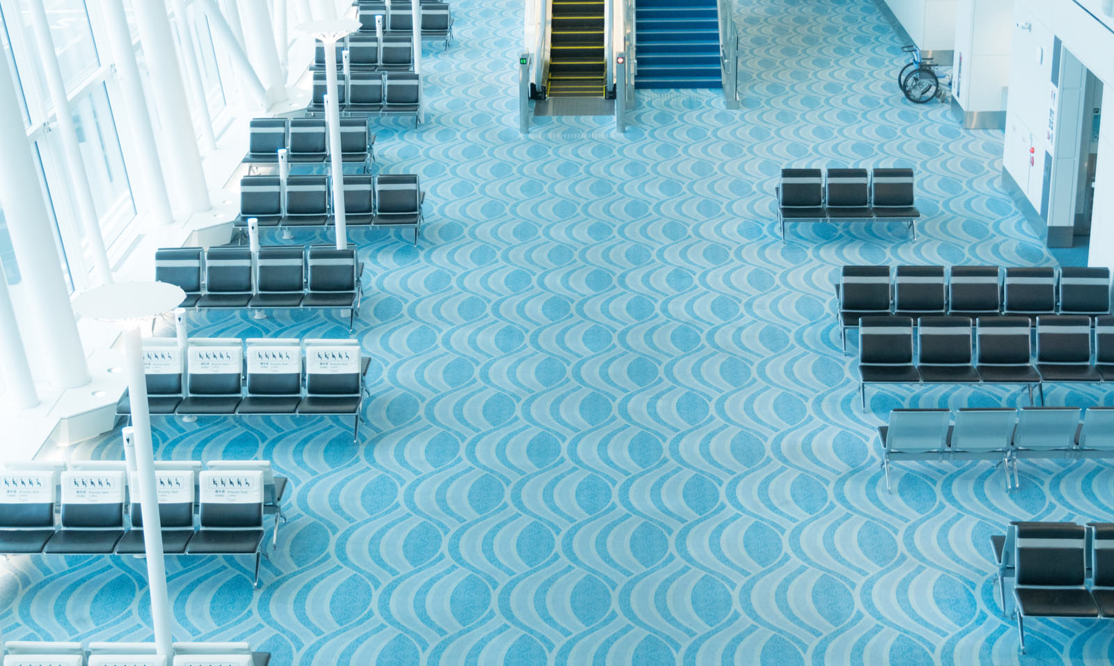 青いタイル床に配置された黒い金属製のベンチ群