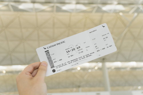 空港のターミナルで搭乗券を手に持つエアポート投稿おじさん