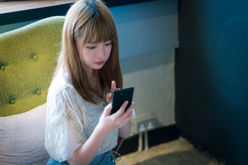 カフェでスマホを見ながらメニューを決める女性