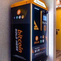 ショッピングモールに設置されたオレンジと黒のビットコイン暗号通貨自動販売機の写真