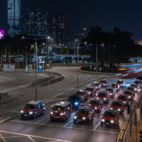 香港の中環（セントラル）の交差点で信号待ちするタクシーの夜景の写真
