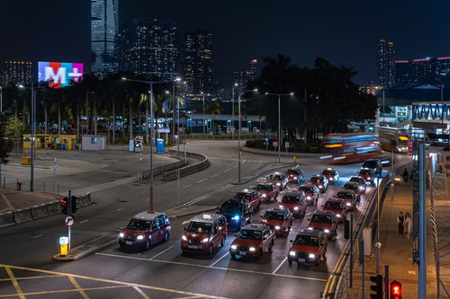 香港の中環（セントラル）の交差点で信号待ちするタクシーの夜景