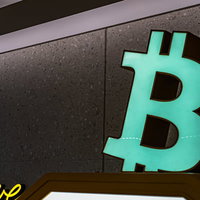 緑色に光るビットコインロゴが掲げられた仮想通貨自動販売機の写真