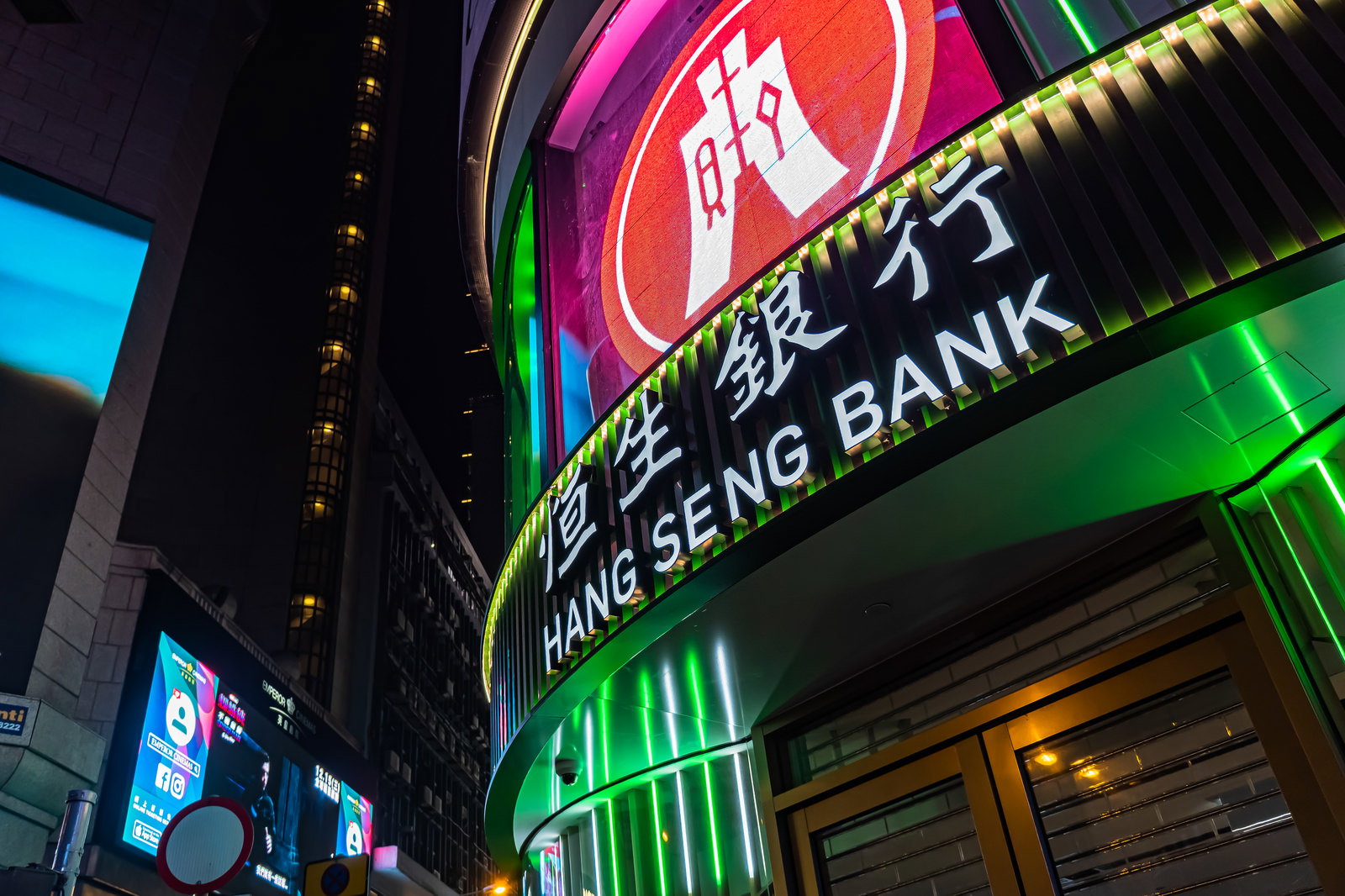 夜の香港の街角で緑色のネオンサインが光るHSBC恒生銀行の建物