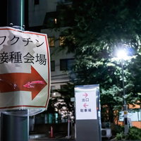 夜間のワクチン接種会場へ案内する矢印看板の写真