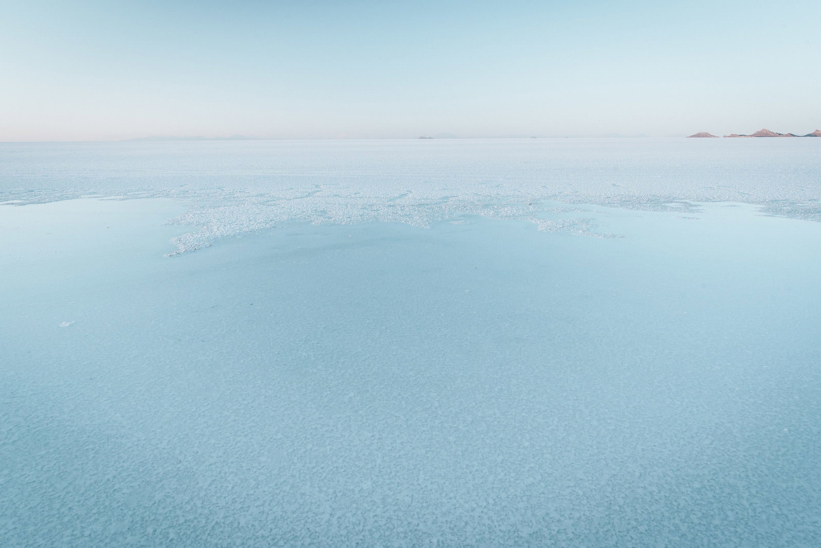 雲の隙間から光が差し込む海と山の風景