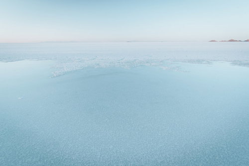 雲の隙間から光が差し込む海と山の風景