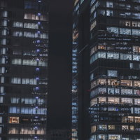 灯りを絶やさぬ夜間のオフィスビル風景と都市景観の写真