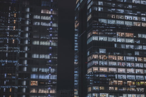 灯りを絶やさぬ夜間のオフィスビル風景と都市景観