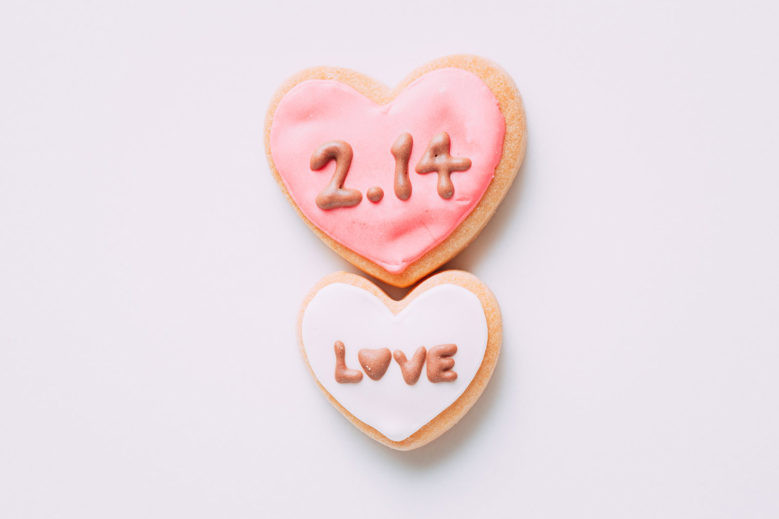 ピンクと白のアイシングが施されたハート型クッキー2枚。上に2.14、下にLOVEの文字