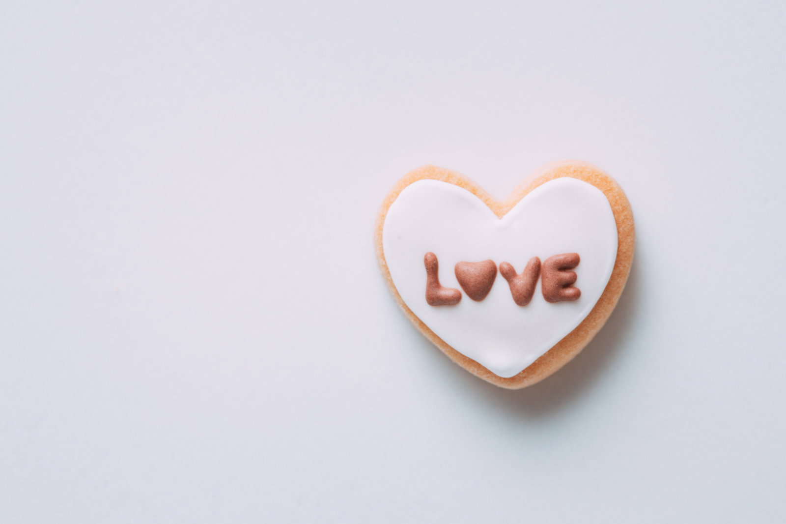 白いハート型クッキーに「LOVE」と書かれたアイシングクッキー