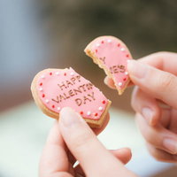 ハッピーバレンタイン終了のお知らせ、ピンク色のハート型アイシングクッキーを割るの写真