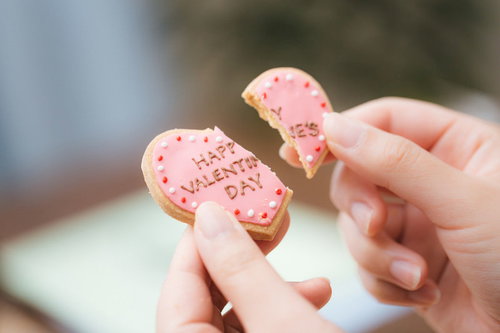 ハッピーバレンタイン終了のお知らせ、ピンク色のハート型アイシングクッキーを割る