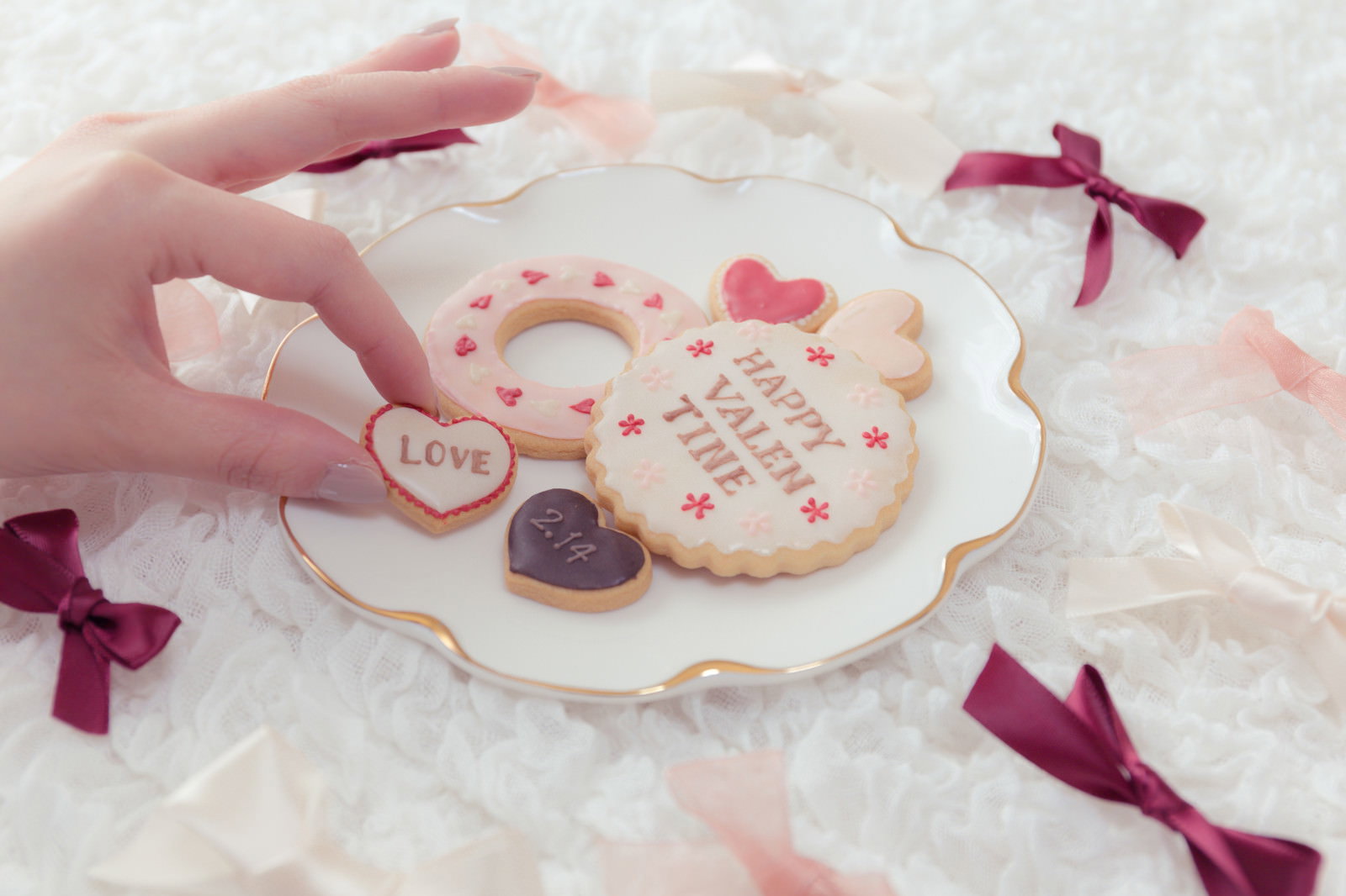 ハート型とドーナツ型のアイシングクッキーを手で掲げる、LOVE,バレンタイン装飾
